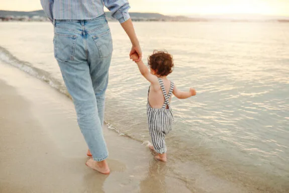 Father walking with toddler son on the beach